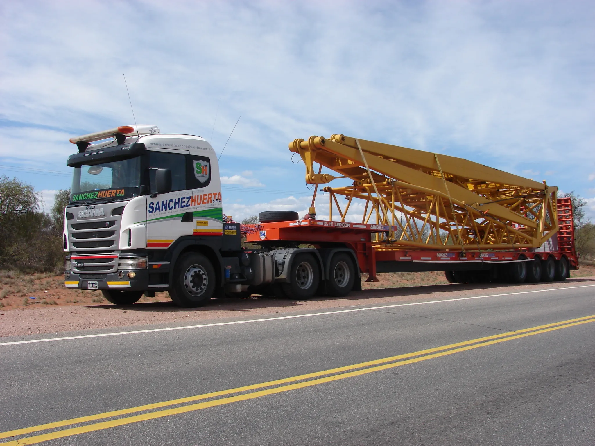 Camión con carretón de baja cama transportando la estructura desarmada de una grúa torre, en la operación minera de Lama