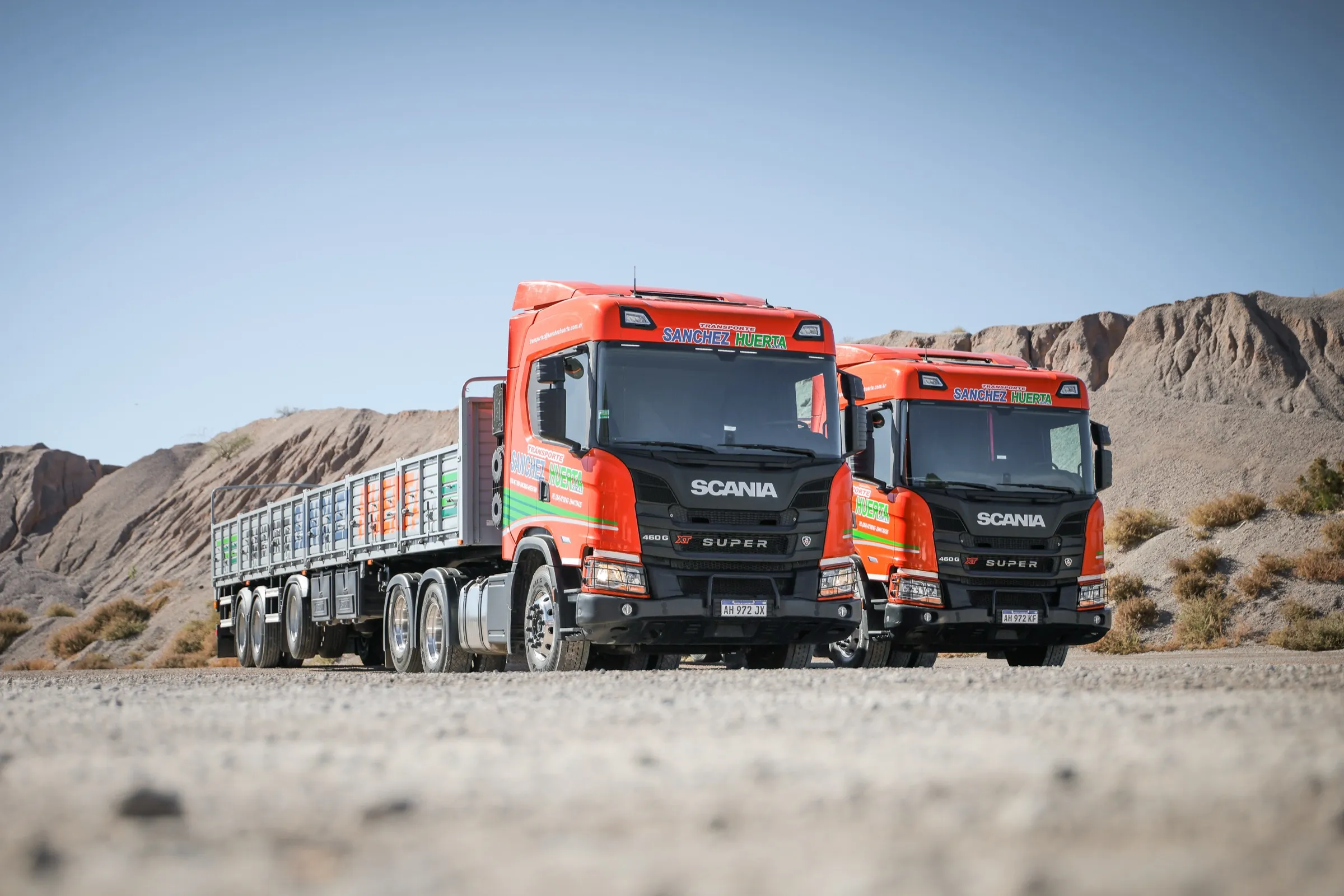 Dos tractores Scania nuevos de la flota de Transporte Sanchez Huerta estacionados en un predio, con cerros áridos al fondo